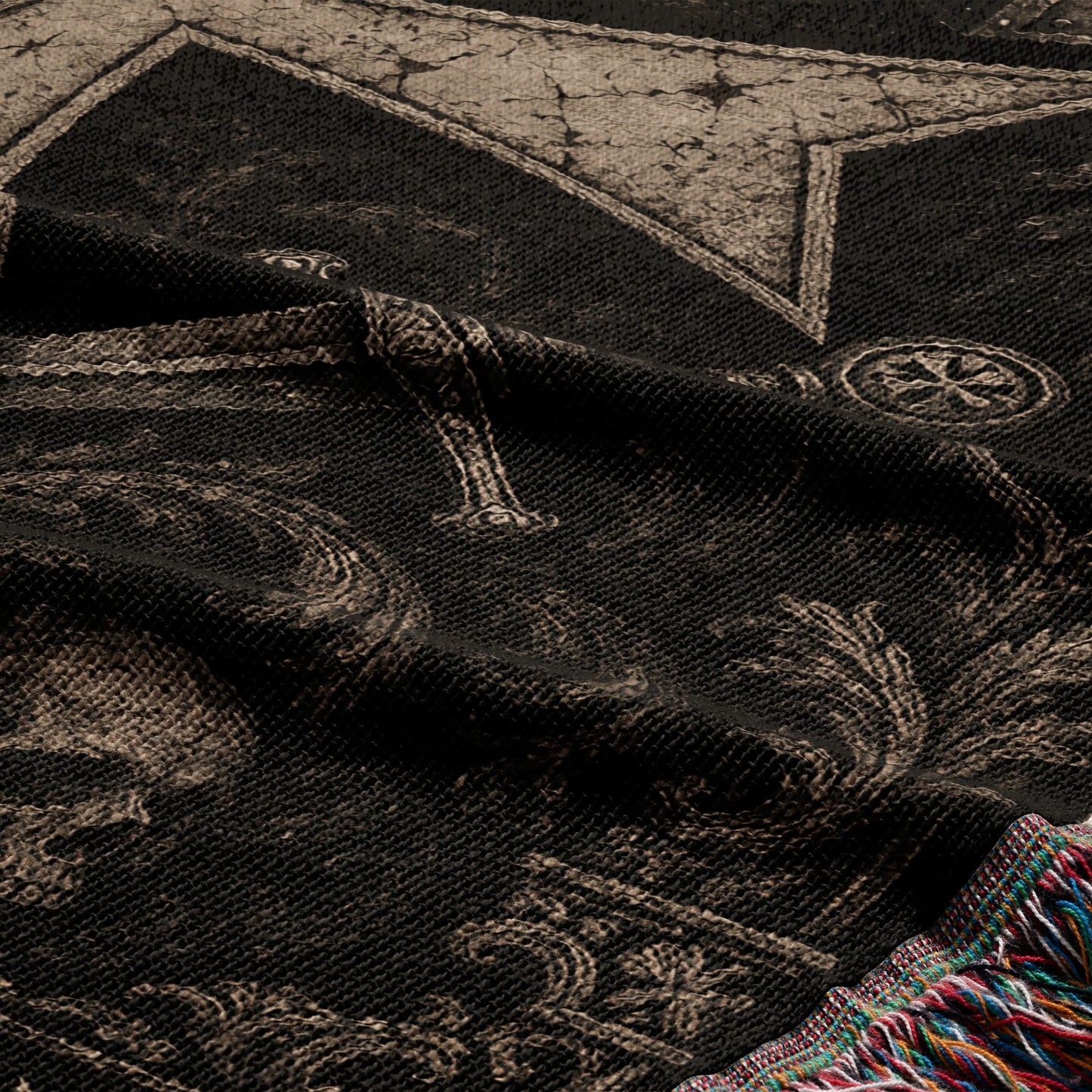 Black blanket with skull and cross motifs, fringed edge.