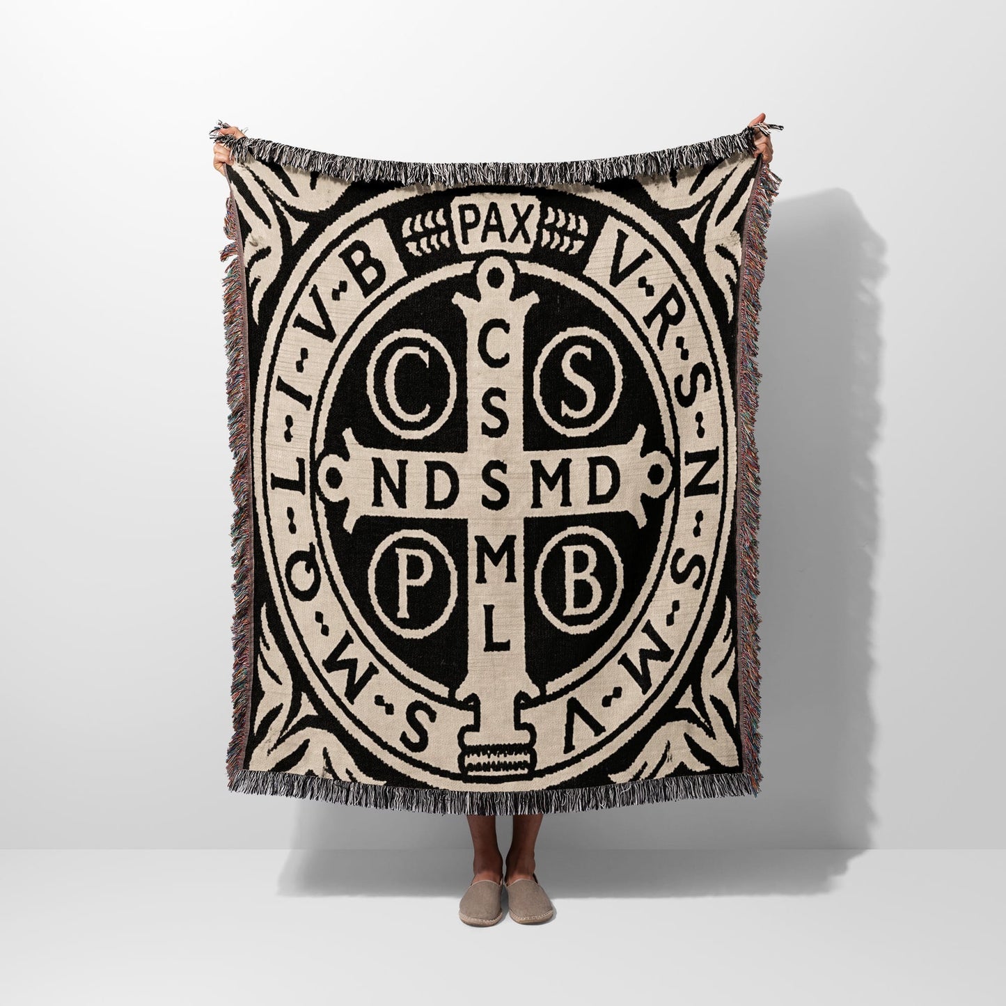 Black and tan woven throw with St. Benedict medal design and fringed edges.