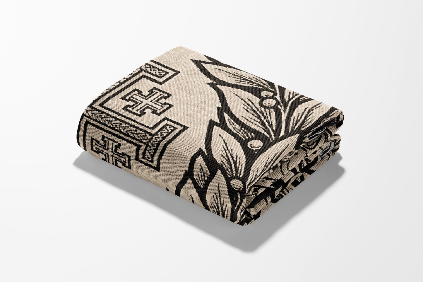 Folded textile with black geometric and floral pattern on a light background.