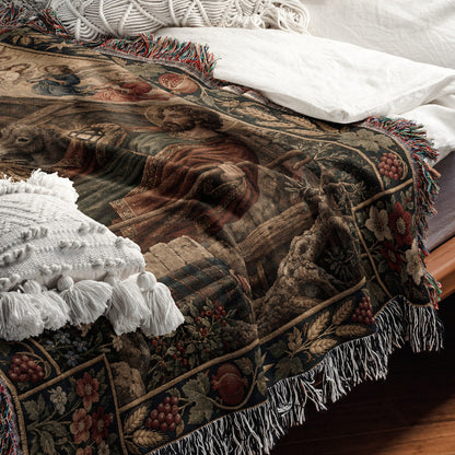 A folded woven throw blanket with a Renaissance art print and fringe rests on a bed.
