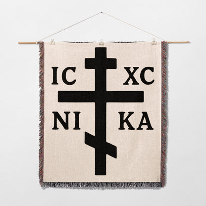 Orthodox Christian cross with IC XC NI KA inscription on a woven blanket.