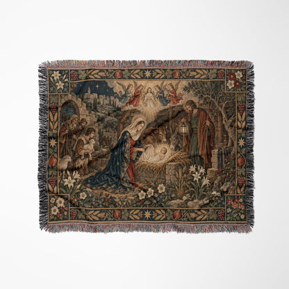 A woven tapestry throw blanket displays a traditional Nativity scene with fringe on the edges.