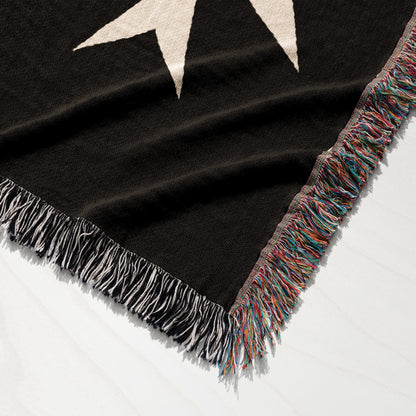 Black woven throw blanket with white stars and fringed edges.