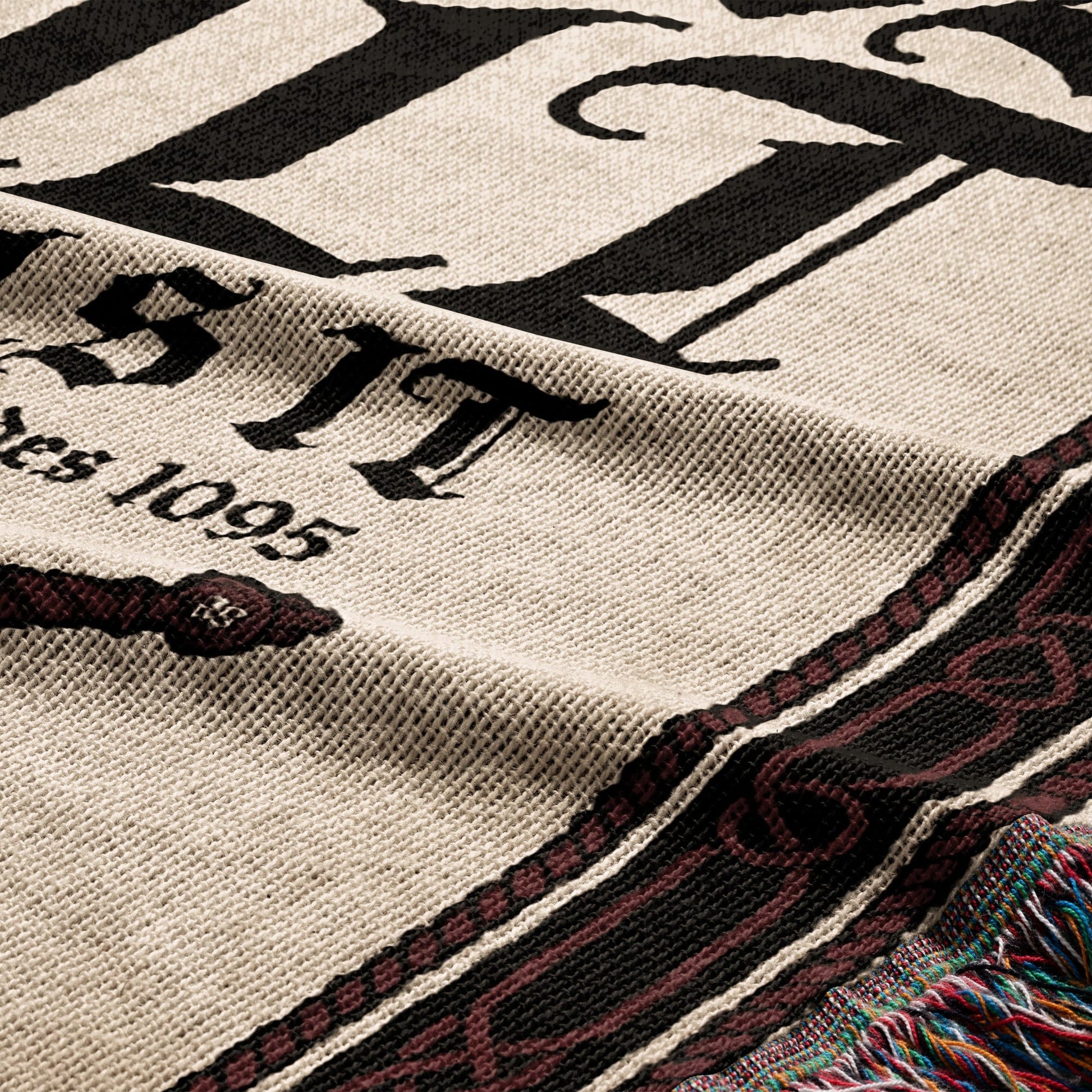 Close-up of a woven blanket with "ESTD 1095" and ornate border.