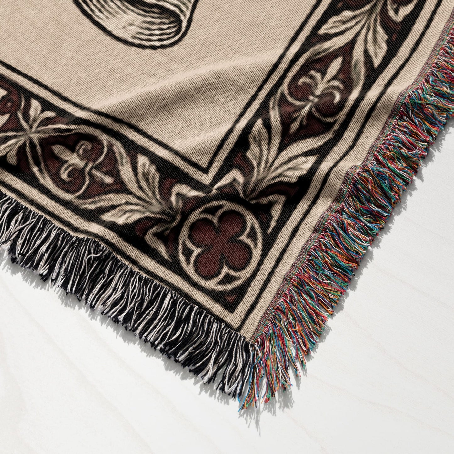 Woven throw blanket with ornate design and black, white, and colorful fringe.