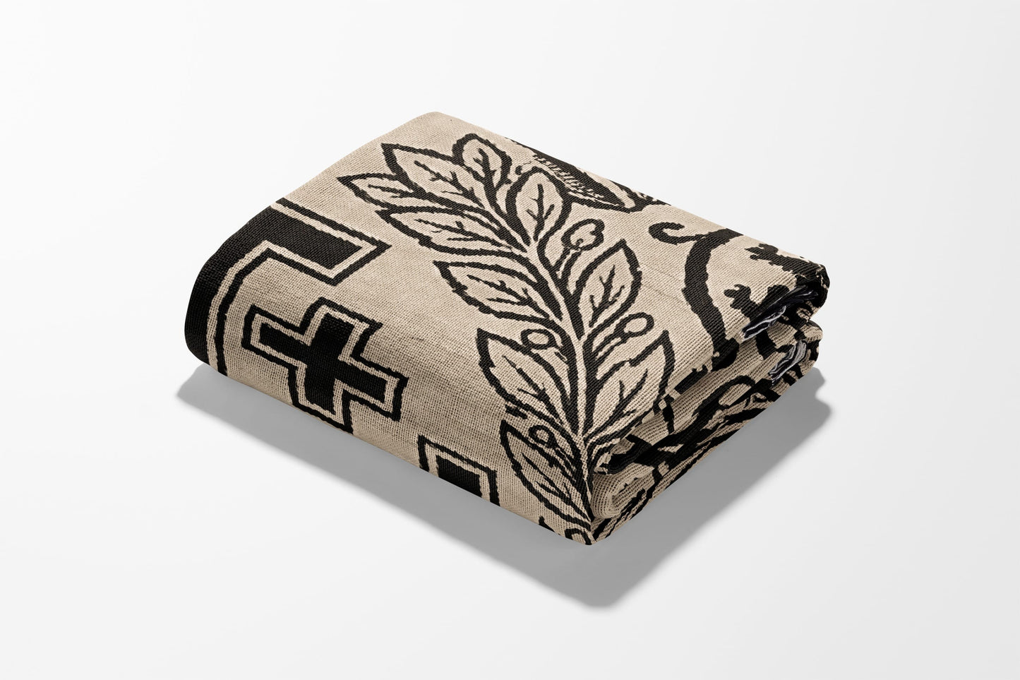 Rolled beige blanket with black geometric and botanical pattern.