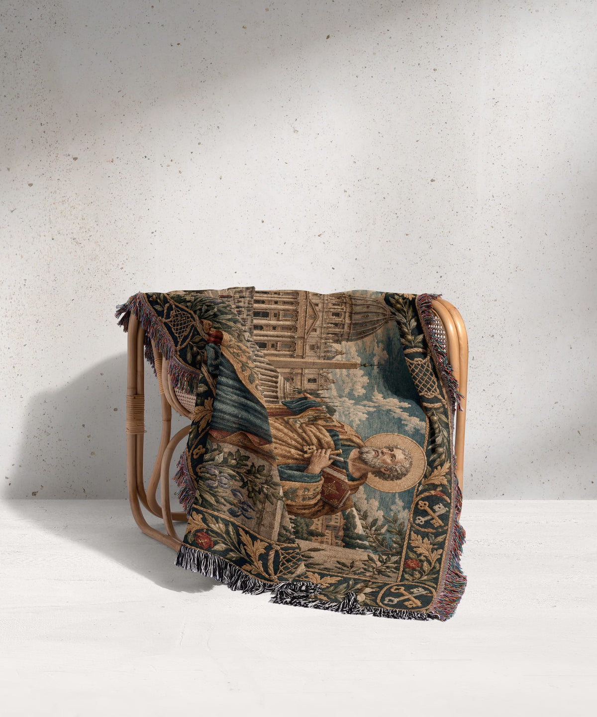 Woven throw blanket depicting Saint Peter holding keys, draped over a light rattan armchair.