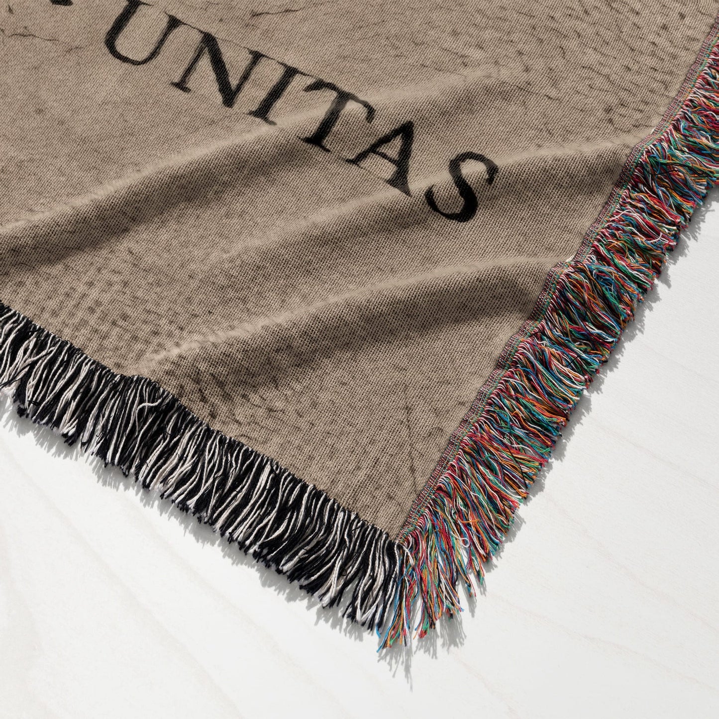Brown woven blanket with colorful fringed edge and "UNITAS" text.