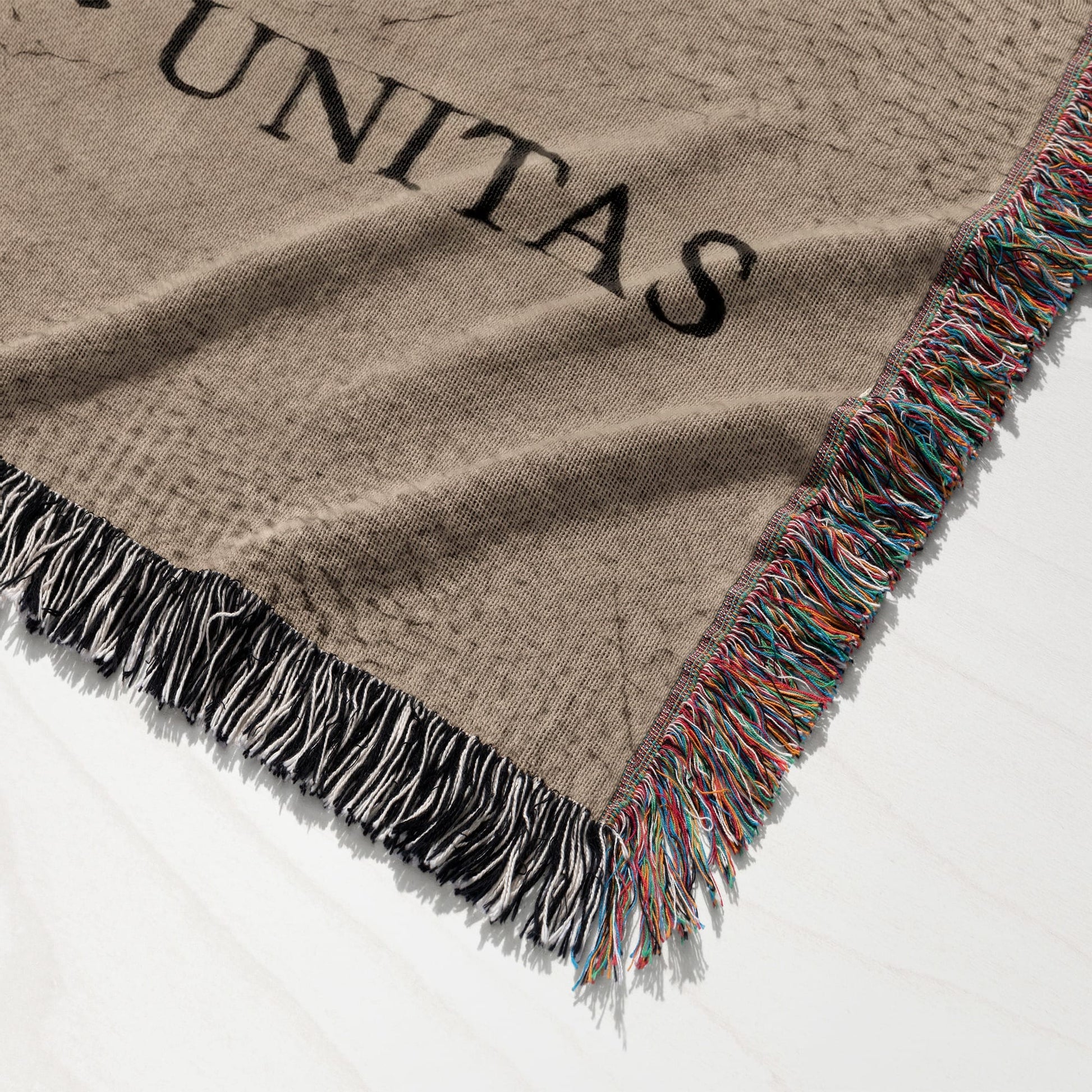 Brown woven blanket with colorful fringed edge and "UNITAS" text.