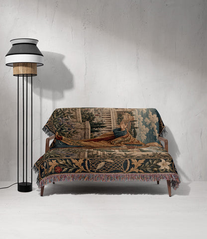 A wooden sofa draped in a classical tapestry featuring a raised hand, next to a black floor lamp against a textured white wall.