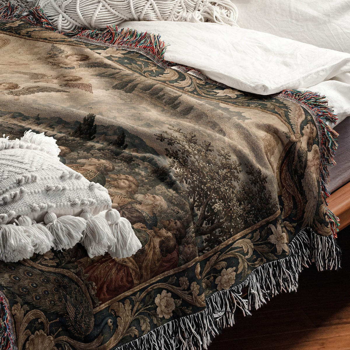 Woven tapestry throw blanket with a Renaissance landscape design and colorful fringed edges draped on a bed.