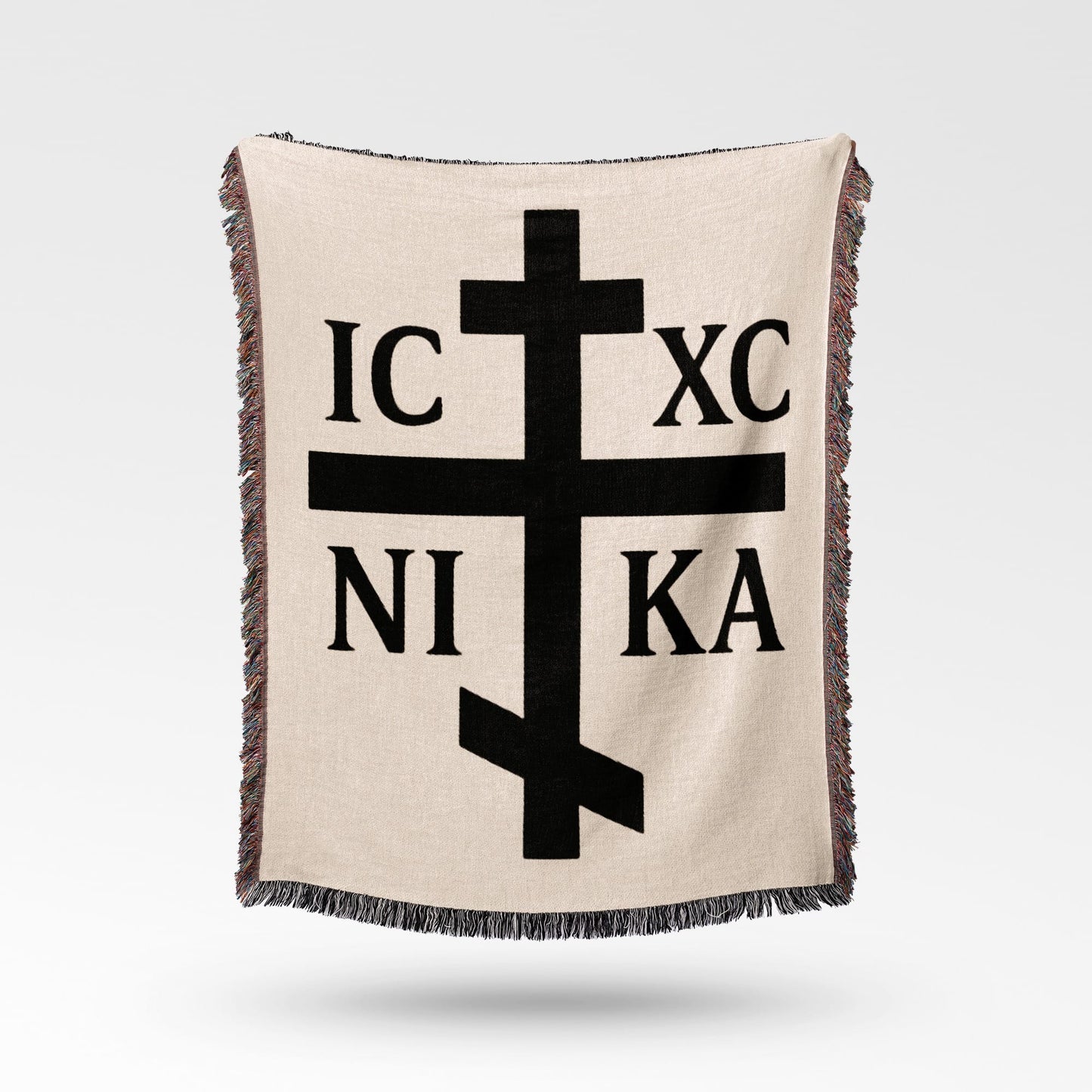 Orthodox Christian cross with IC XC NIKA text, on beige blanket.