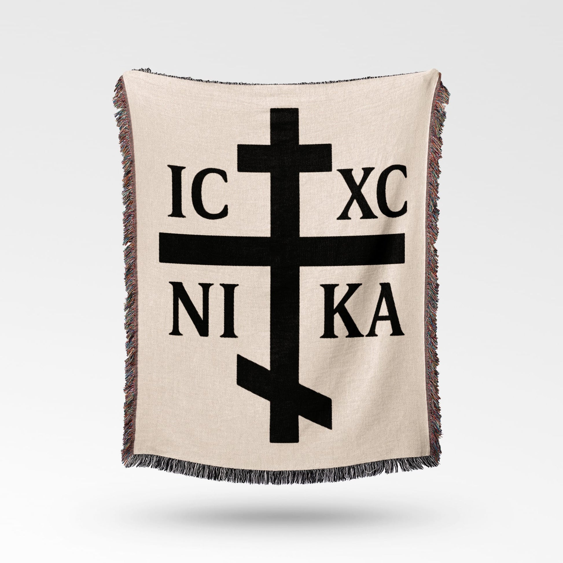 Orthodox Christian cross with IC XC NIKA text, on beige blanket.
