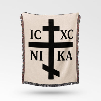 Orthodox Christian cross with IC XC NIKA text, on beige blanket.