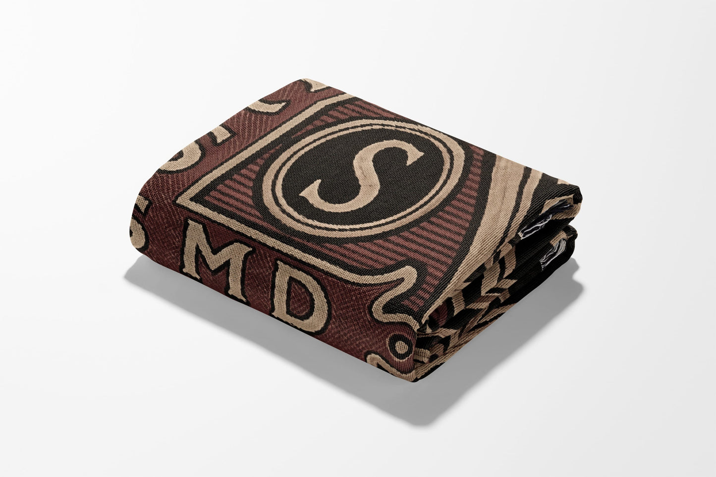 Folded blanket with "S" and "MD" text in brown, black, and tan.