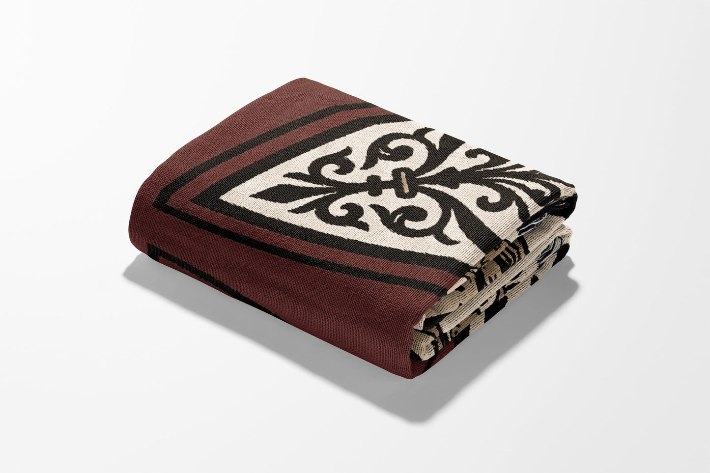 Folded burgundy throw blanket with black and cream ornate pattern on white background.