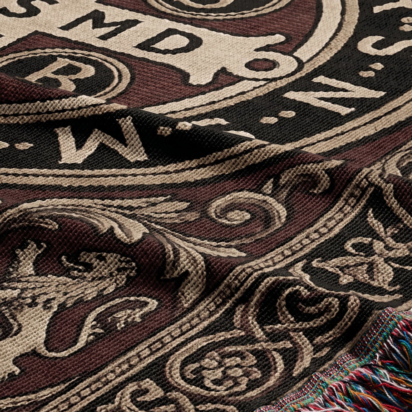 Tapestry blanket with intricate brown, black, and cream pattern and colorful fringed edge.