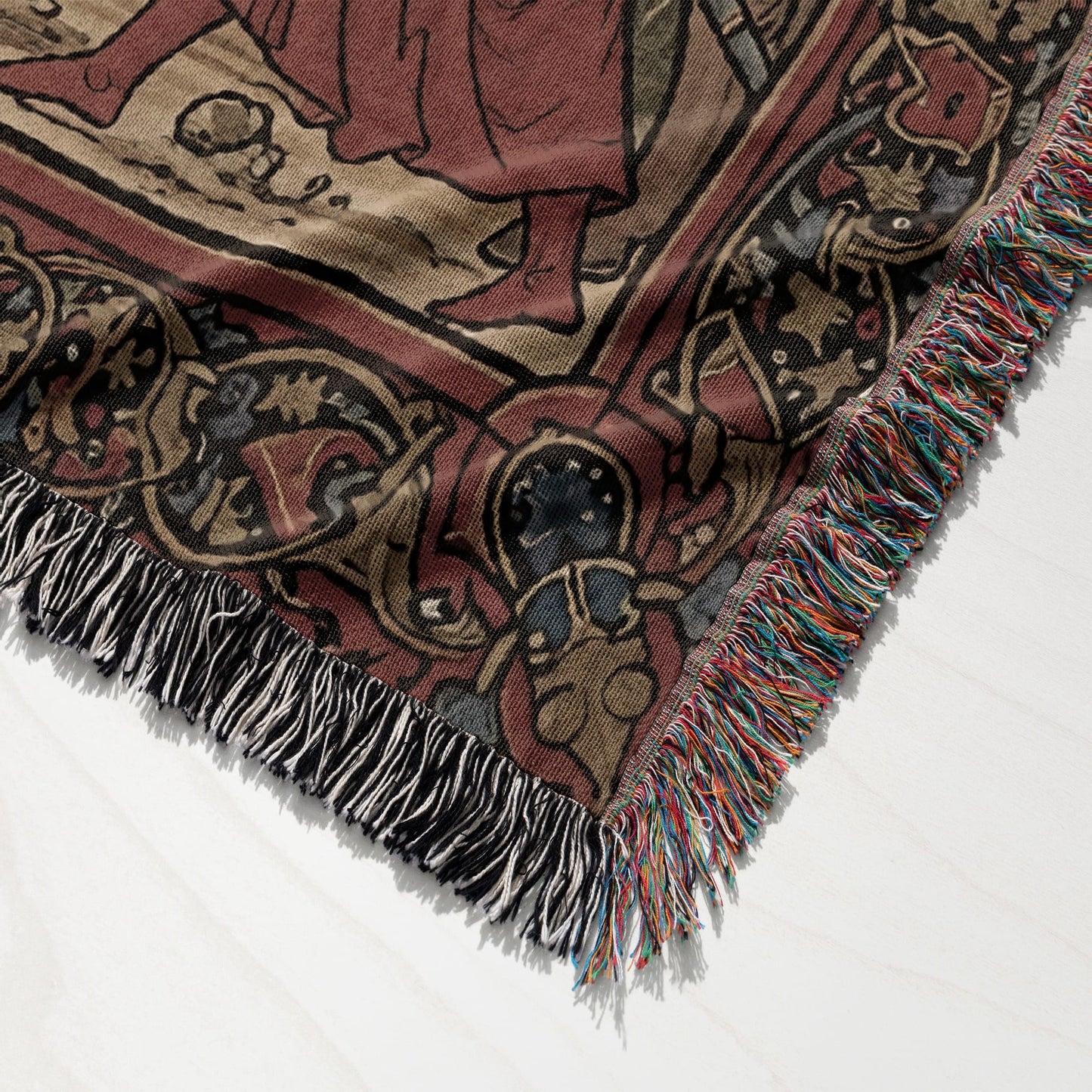 Woven tapestry blanket corner with fringe, featuring intricate medieval-style patterns.