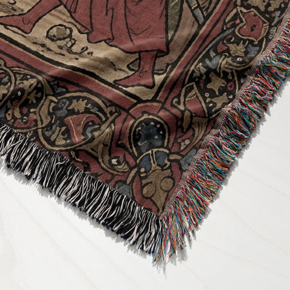 Woven tapestry blanket corner with fringe, featuring intricate medieval-style patterns.