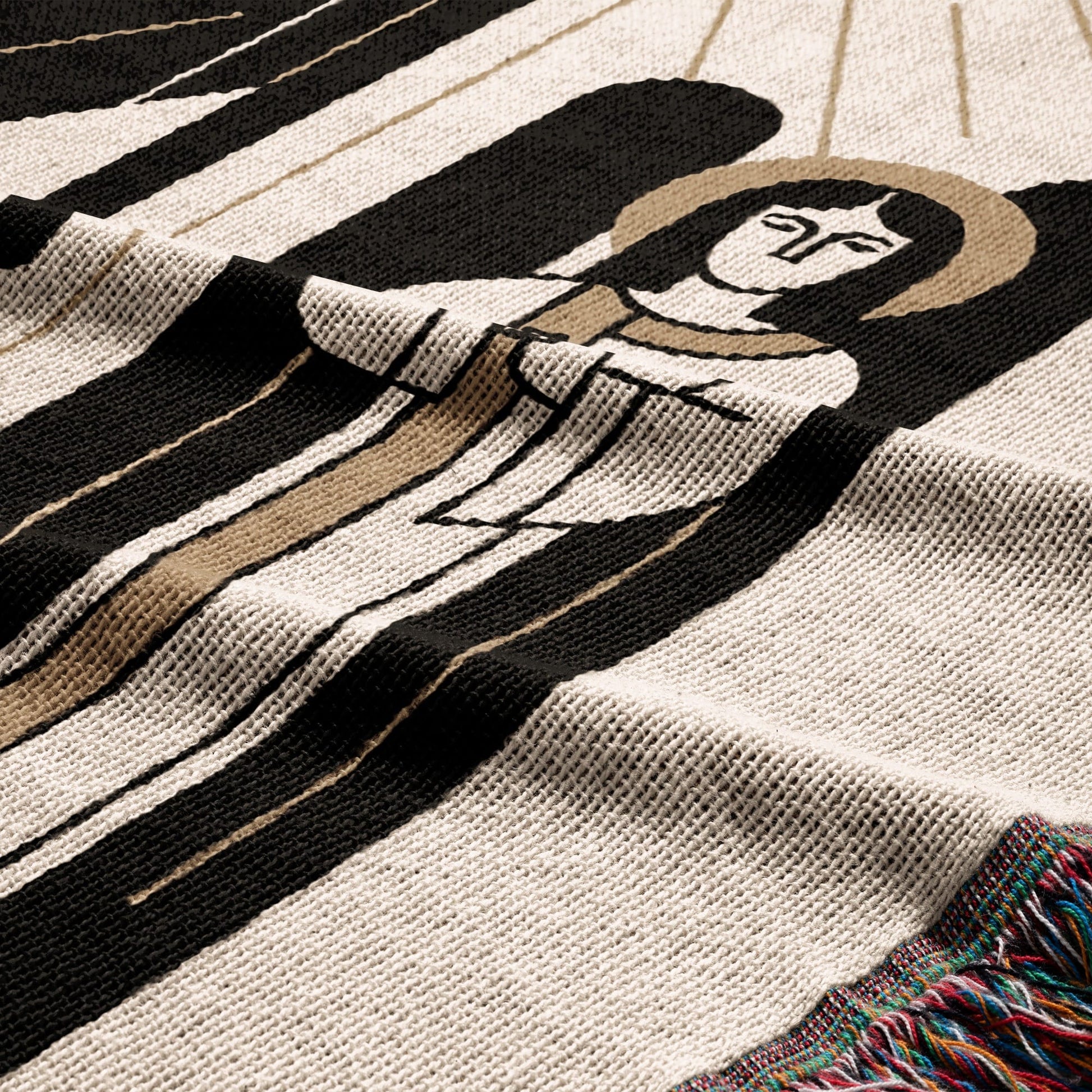 Woven blanket with a stylized angelic figure in black and tan on a cream background.