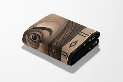 Folded blanket with a portrait of a person's eye and geometric border.