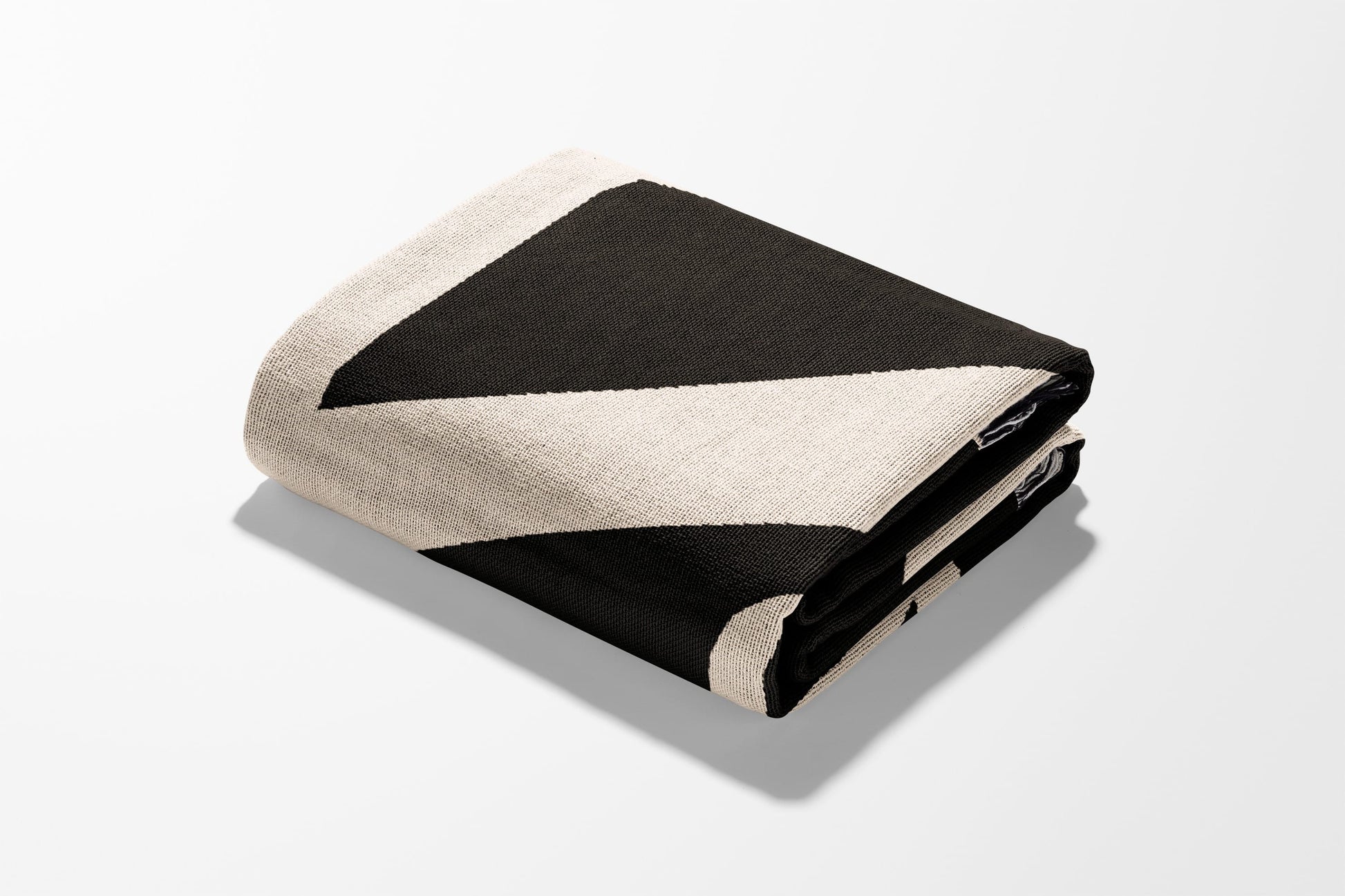 Folded throw blanket with a black and cream geometric stripe pattern.
